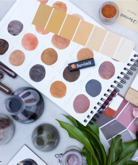 caderno catalogo tintas itens paleta cores suvinil Caderno com círculos coloridos. Em cima dele está uma página do leque Suvinil com cores amarelas de diferentes tons e o COLORi.