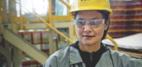 colaboradora epi fabrica suvinil Colaboradora com capacete e óculos de proteção (EPI) em uma fábrica da Suvinil.